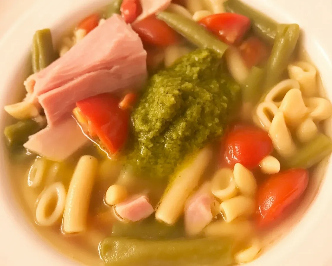 Soupe au pistou servie avec pesto maison, légumes frais et pâtes.