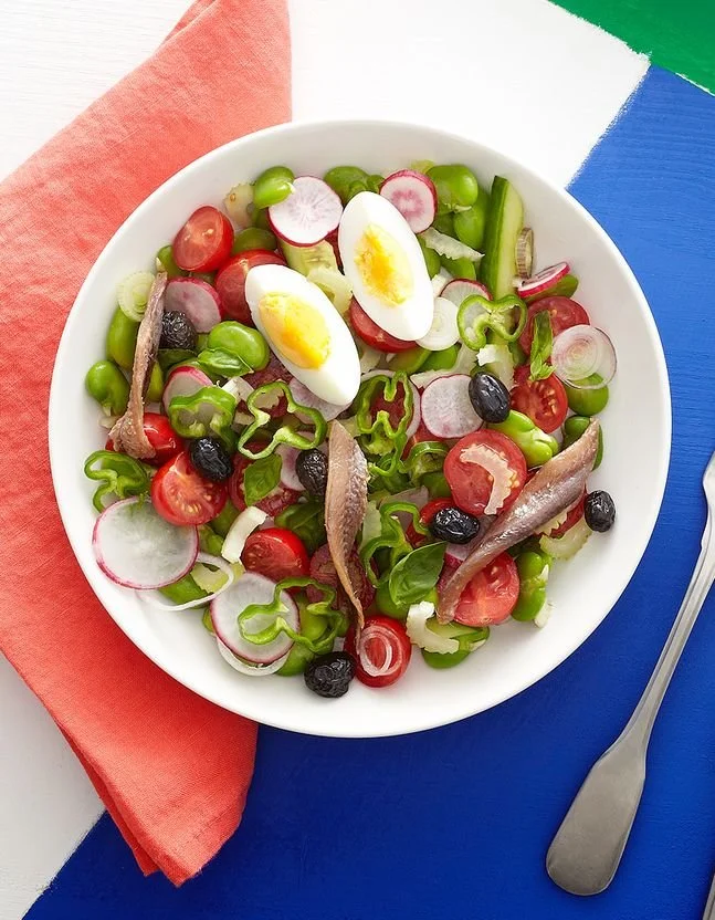Recette de salade niçoise avec tomates, olives, thon et légumes frais.